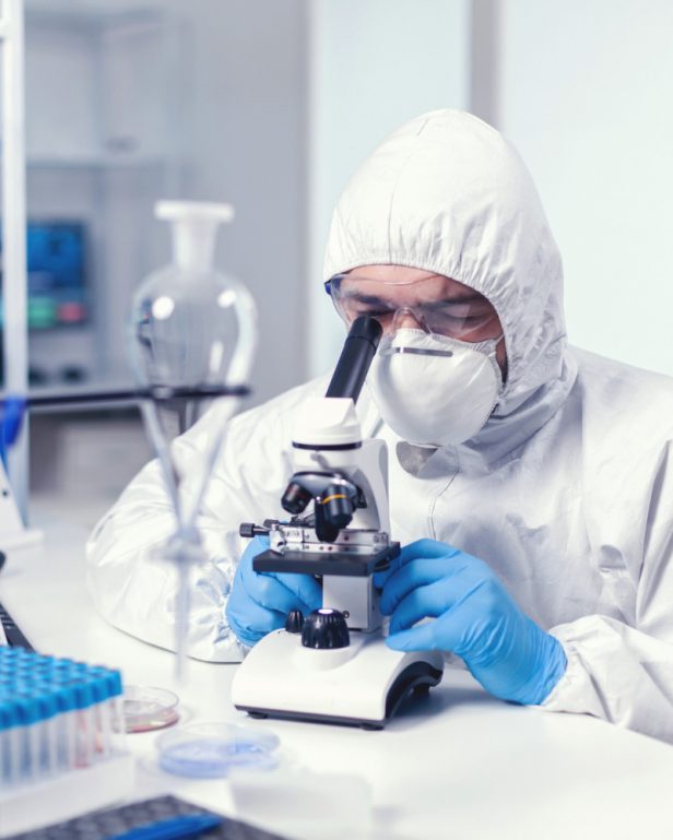 analyzing-virus-in-microbiology-lab-using-microscope-wearing-ppe-suit-and-glasses analyzing-virus-in-microbiology-lab-using-microscope-wearing-ppe-suit-and-glasses